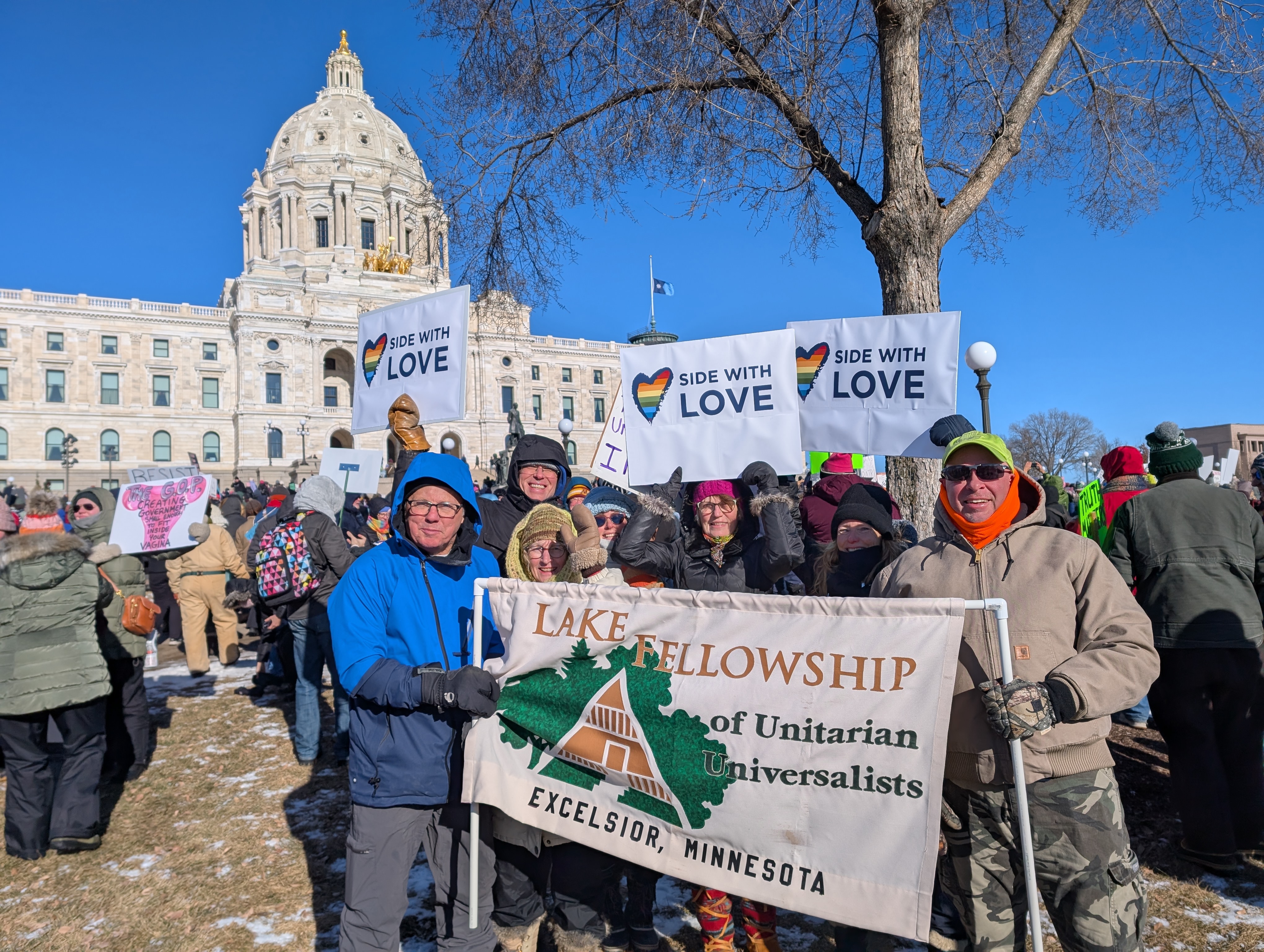 Lake Fellowship members standing in front of a Lake Fellowship banner with the Minnesota Capitol in the background