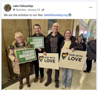 Four adult members of LFUU stand in a line holding signs at the state capitol: a short elderly woman holds a green sign with white letters "I am an equality voter," medium height young male holds a green sign with white letters "I am an equality voter," medium height middle-age male holds a white sign with a rainbow heart and black letters "Side with Love," medium-height young female holds a white sign with a rainbow heart and black letters "Side with Love."