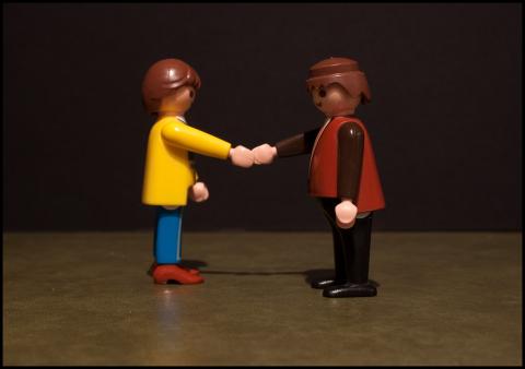 photo of two plastic toy figures shaking hands