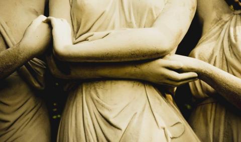 Close up photo of a statue of three figures holding hands
