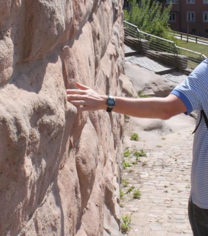 photo of a person touching a very old stone wall