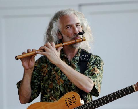 photo of musician Michael Monroe playing a flute while holding a guitar