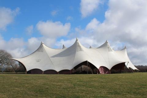 photo of a large, open-sided tent in a field.