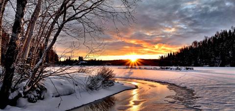 Photo of a sunset over a nearly frozen river in winter.