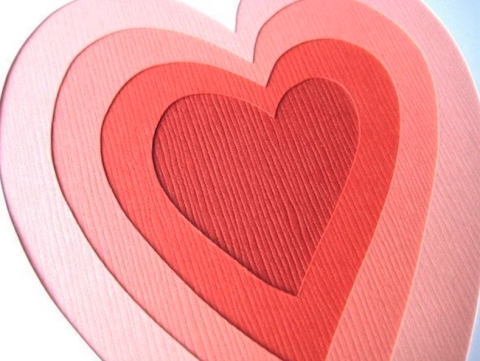 photo of a layered paper artwork of concentric pink to red hearts