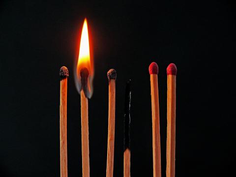 photo of matches, one of which is lit, two of which are unlit, and 3 of which have burned out