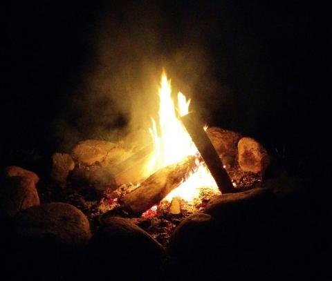 photo of a fire in a stone fire pit, against a black, night backdrop