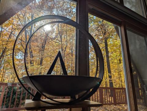 photo of the Lake Fellowship chalice in the foreground, with the A-frame windows behind revealing golden fall foliage