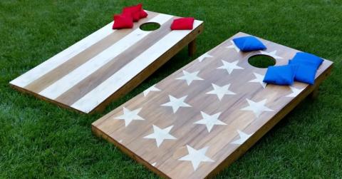 two cornhole boards with corn bags on a grassy lawn
