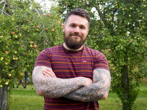 Chris Stedman standing in an apple orchard